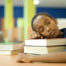 Child napping on stack of books.